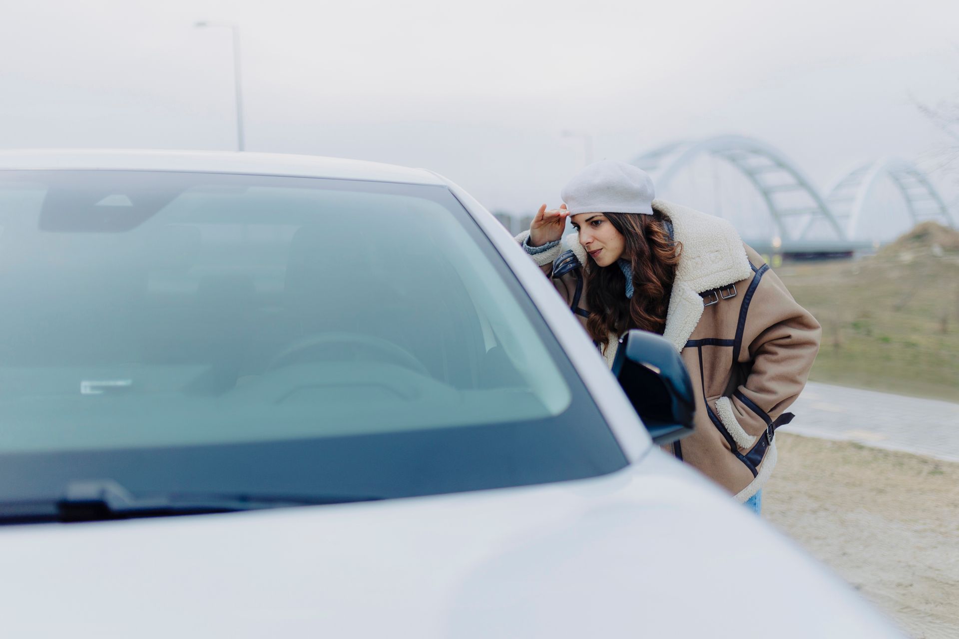 A woman is standing next to a white car.