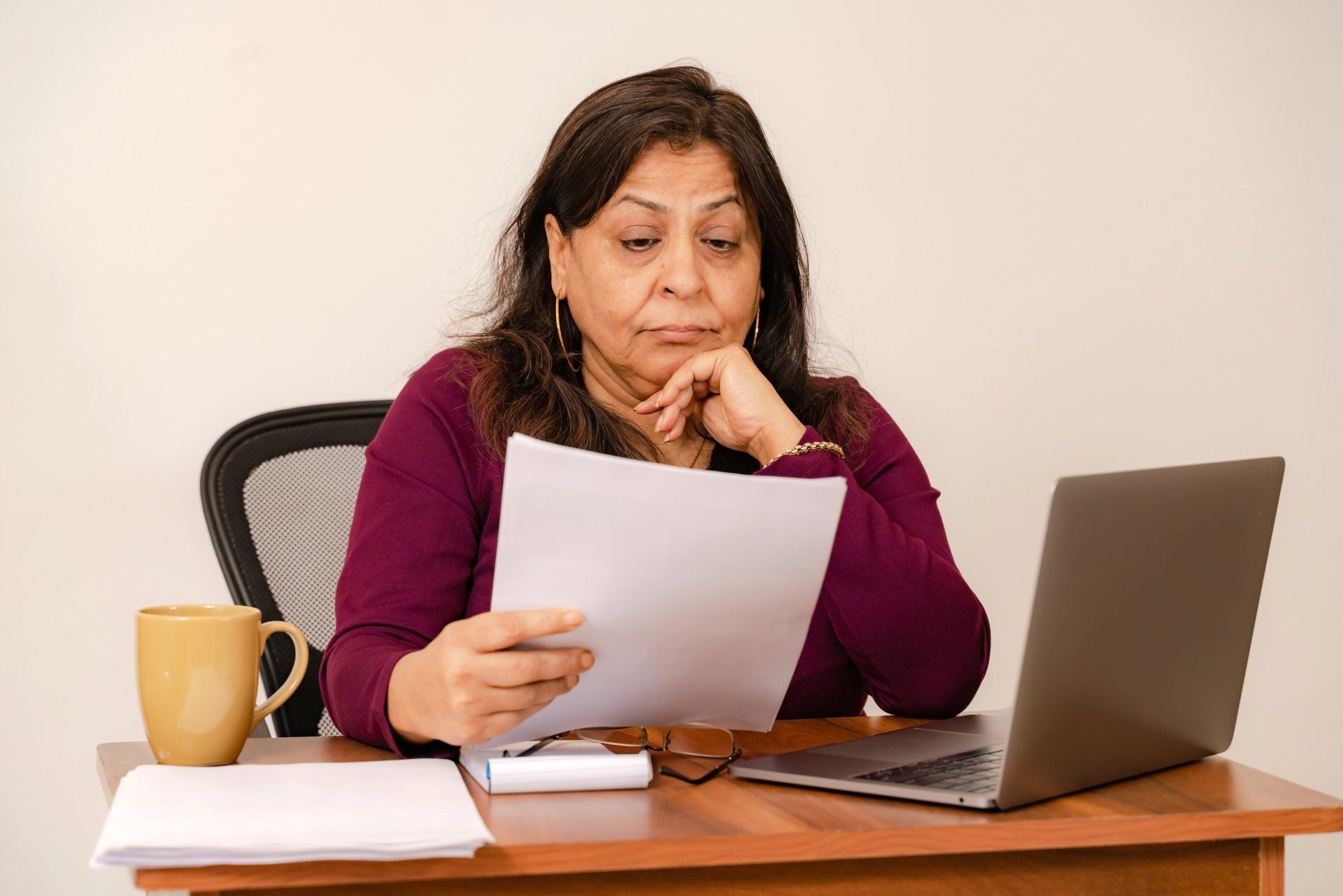 A person sits at a desk, resting their head on their left hand with a surprise medical bill in their right hand.
