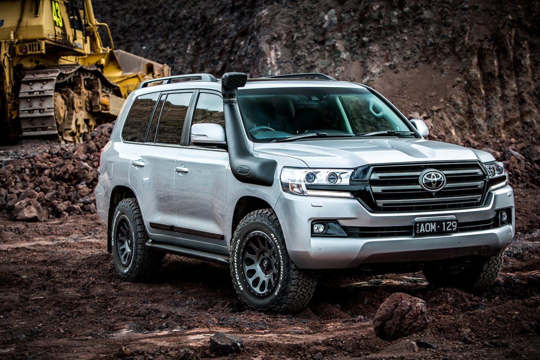 A Silver Toyota Land Cruiser is Parked in the Mud Next to a Bulldozer — Westlakes 4x4 Centre In Toronto, NSW