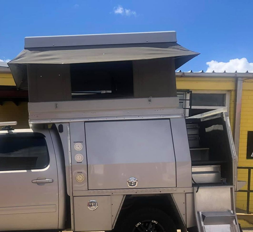 A Truck With a Tent on Top of It is Parked in Front of a Yellow Building — Westlakes 4x4 Centre in Singleton, NSW