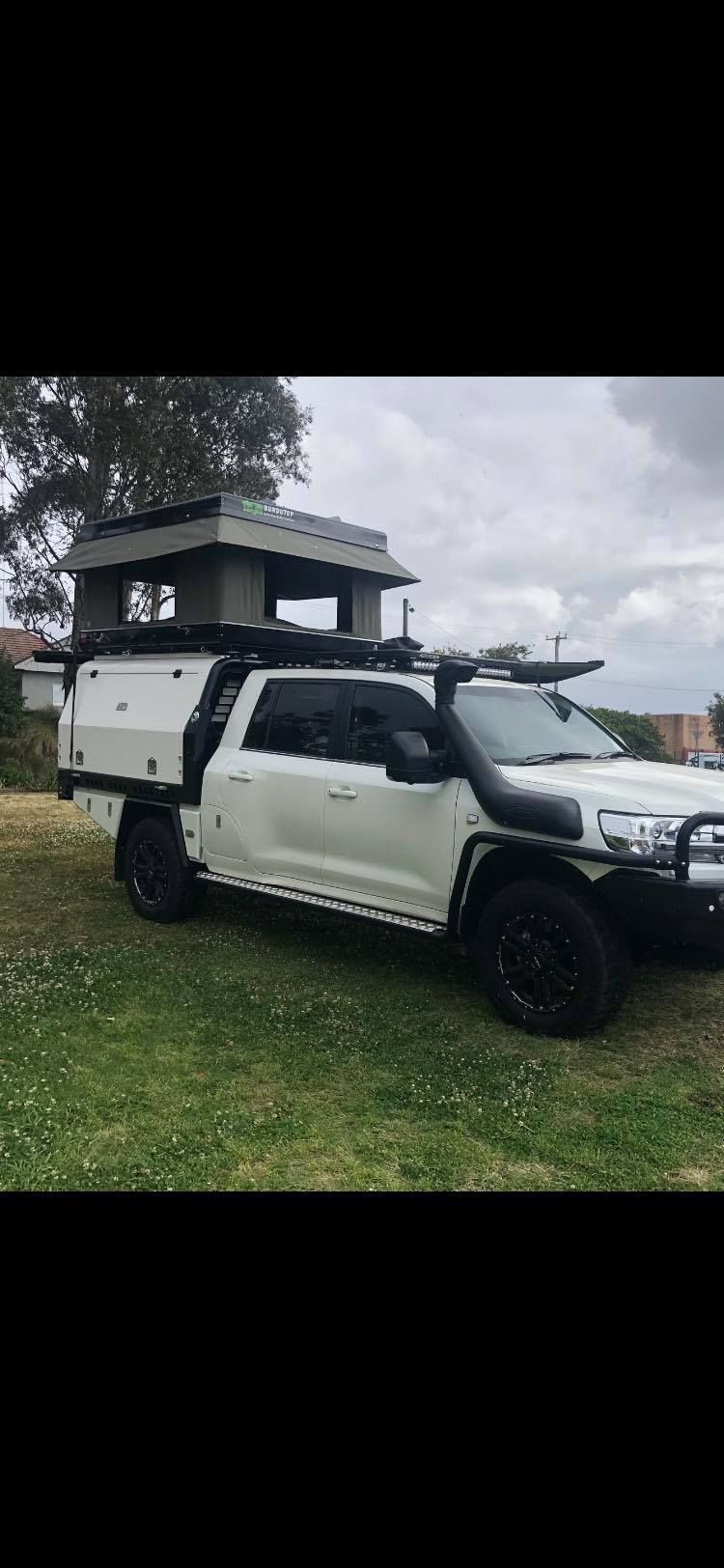 A White Truck With a Tent on Top of It is Parked in a Grassy Field — Westlakes 4x4 Centre in Singleton, NSW