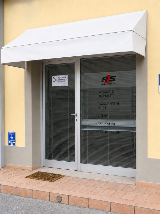 Ingresso del negozio con doppie porte a vetri, tenda da sole bianca e parete esterna beige.
