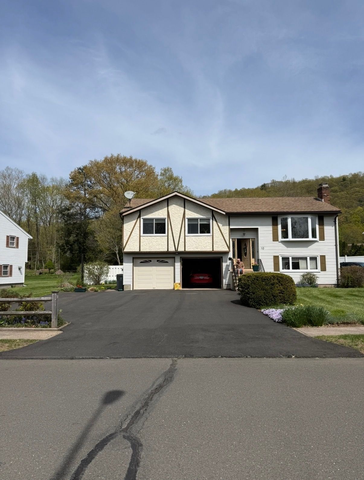 Suburban house with a driveway and garage under a blue sky, viewed from the street