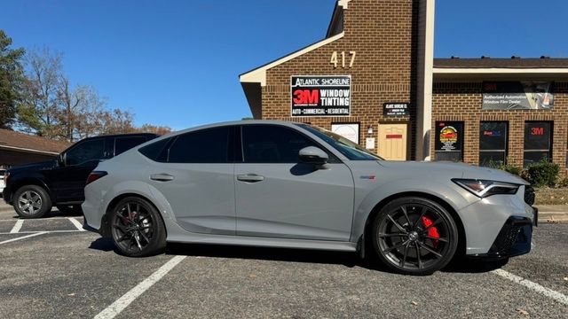 Gray car with tinted windows parked outside a building with tinting services.
