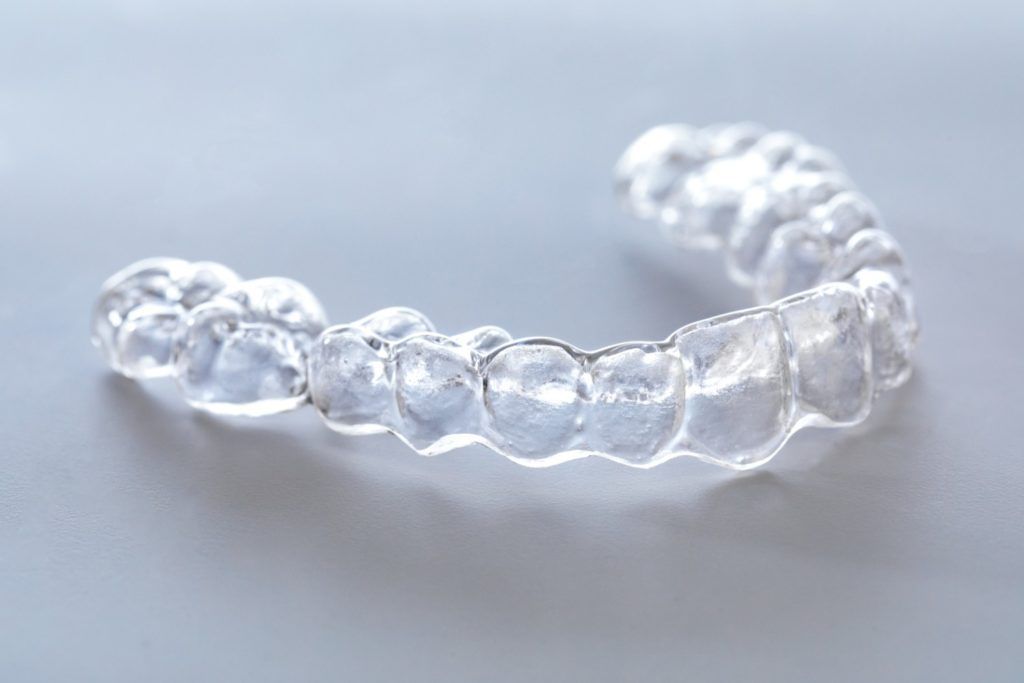 Clear plastic dental aligner on a light gray surface