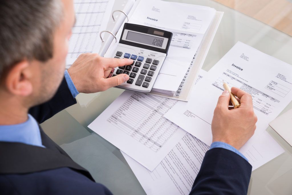 Person using a calculator over financial documents on a desk