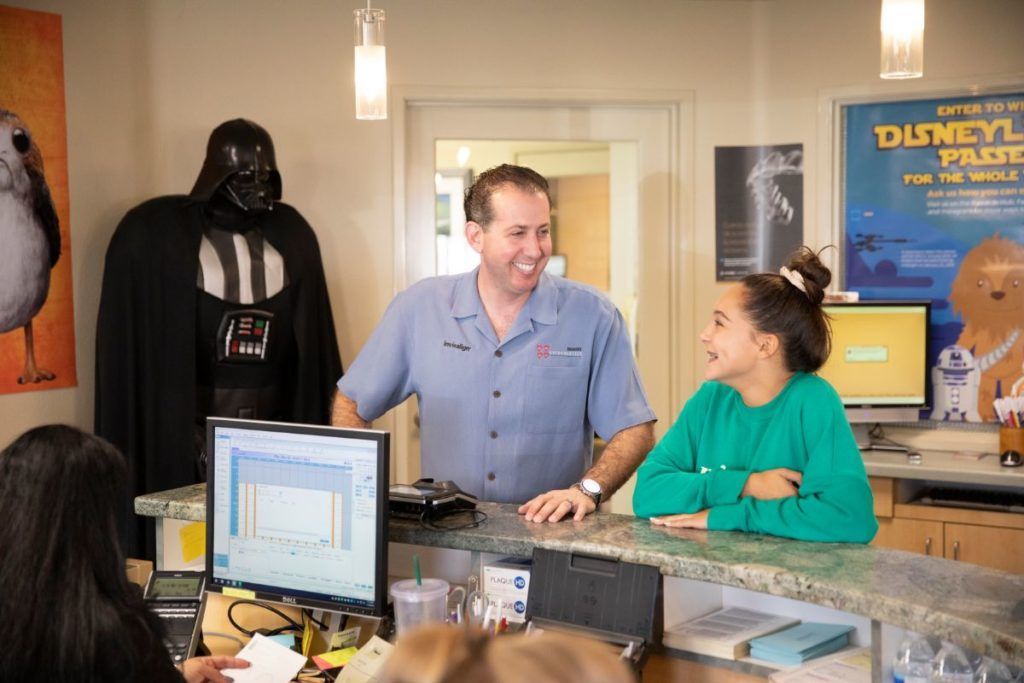 Two people talking behind a café counter with a Darth Vader statue in the background.