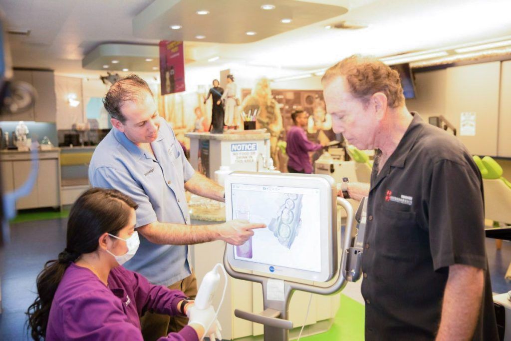 People gathered around an interactive touchscreen display in a bright indoor exhibition space.