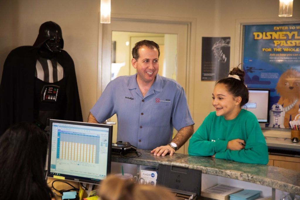 Two people behind a counter with a Darth Vader figure and a Disney poster in a shop