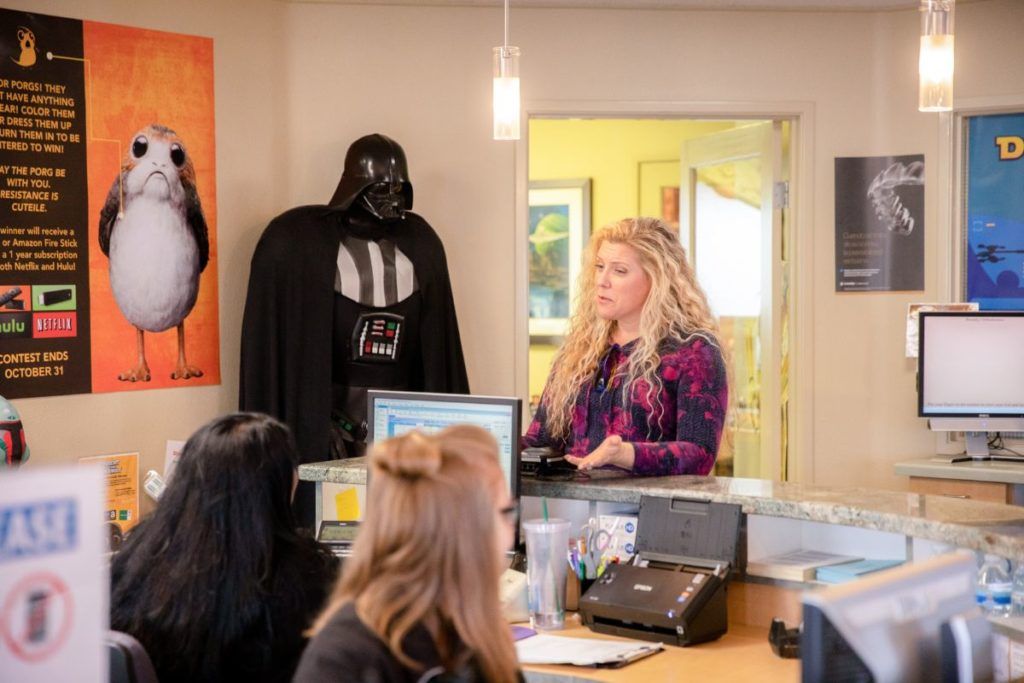 Costume shop counter with Darth Vader and a stormtrooper poster, customer standing at the register