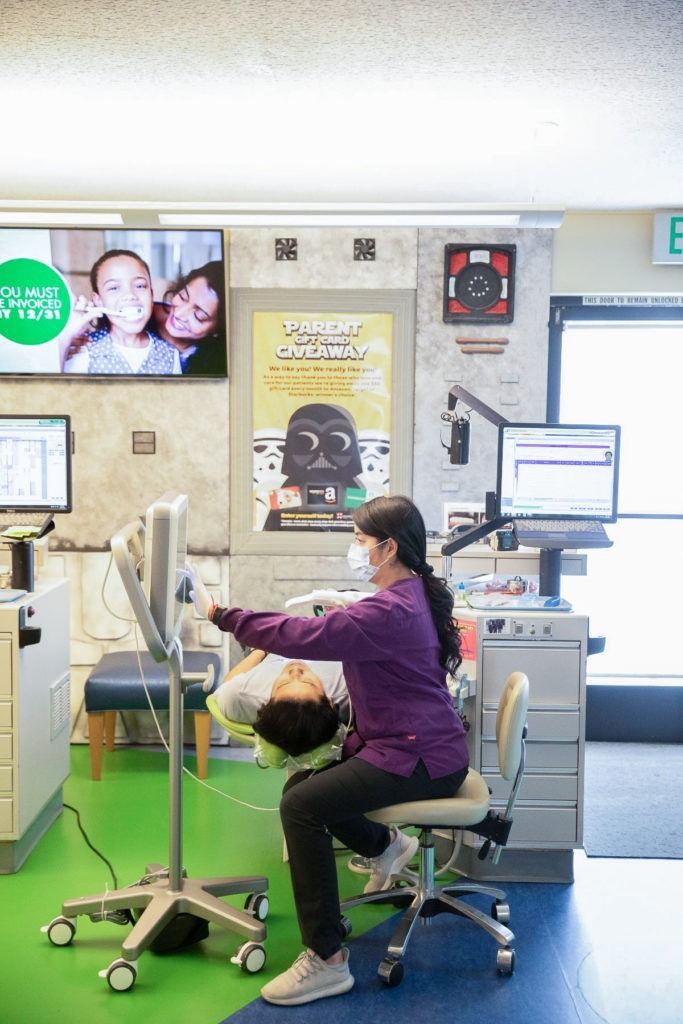 Woman seated at an office workstation with multiple monitors in a bright, modern workspace