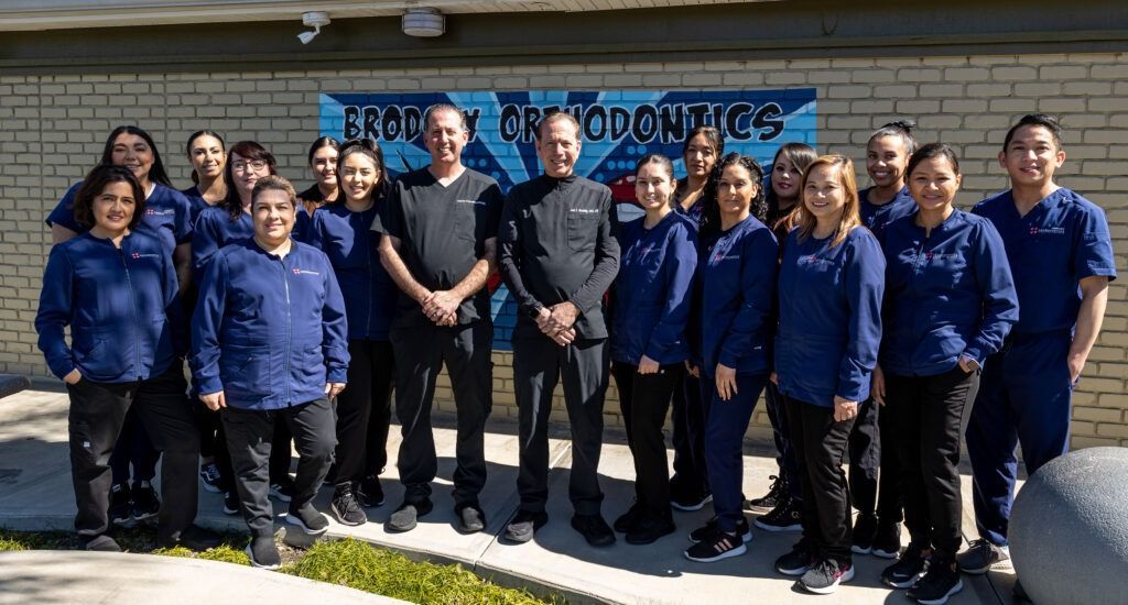 Group of people in blue jackets standing outdoors in front of a school sign.