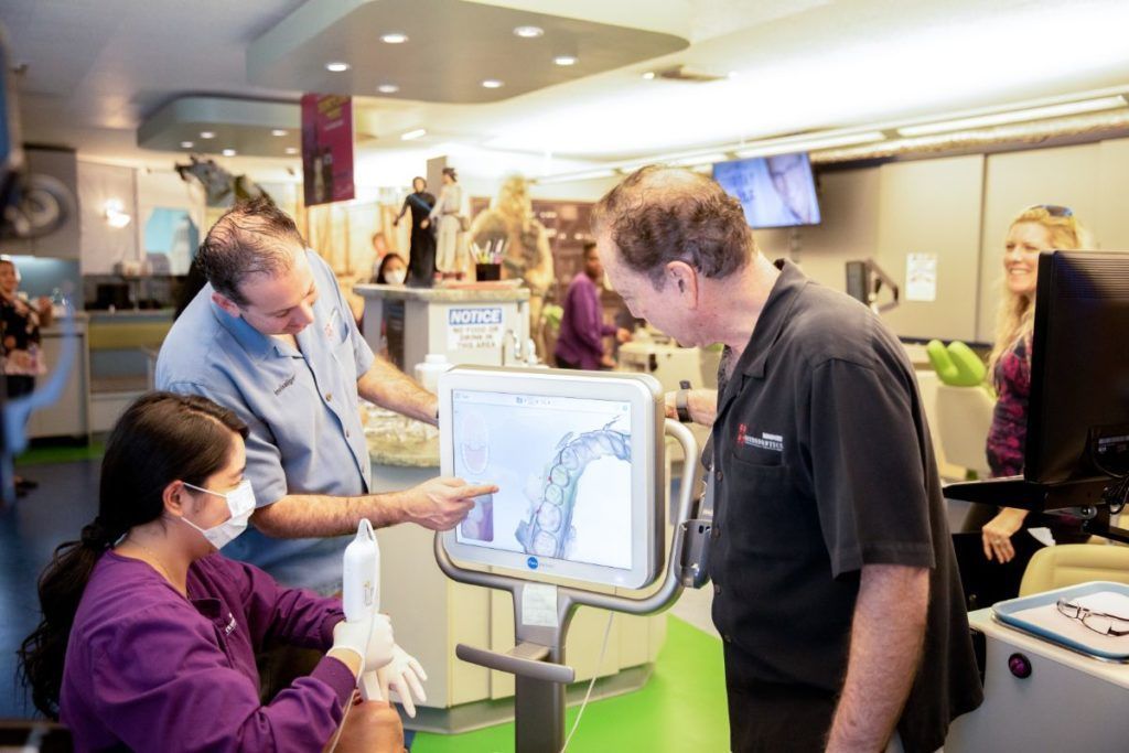 People gathered around a touchscreen in a bright office, discussing a displayed chart.