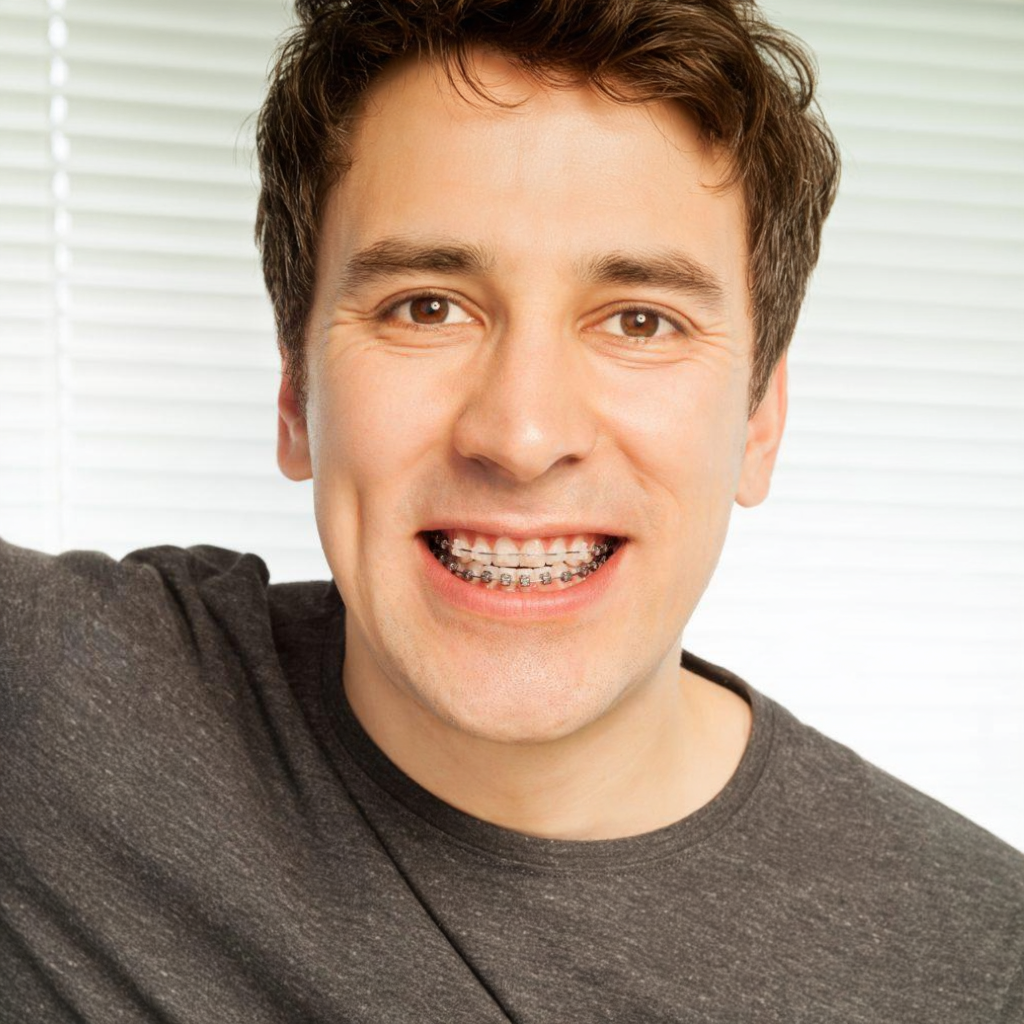 Smiling man showing metal braces against a bright white background