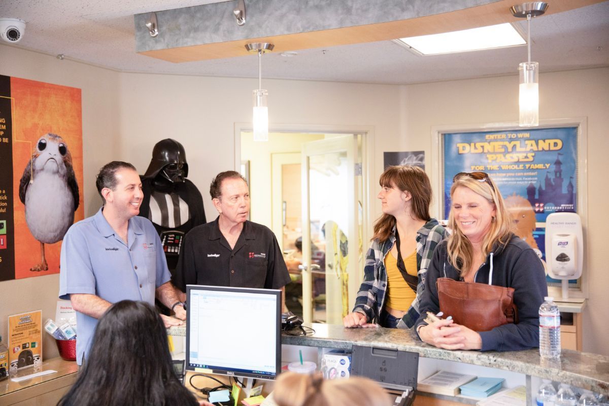 Four people standing behind a counter in a bright office, with a computer and a fish tank in the foreground.