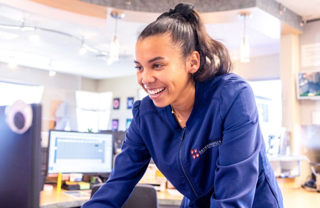 Smiling worker in a blue uniform leaning over a desk in a bright office or clinic