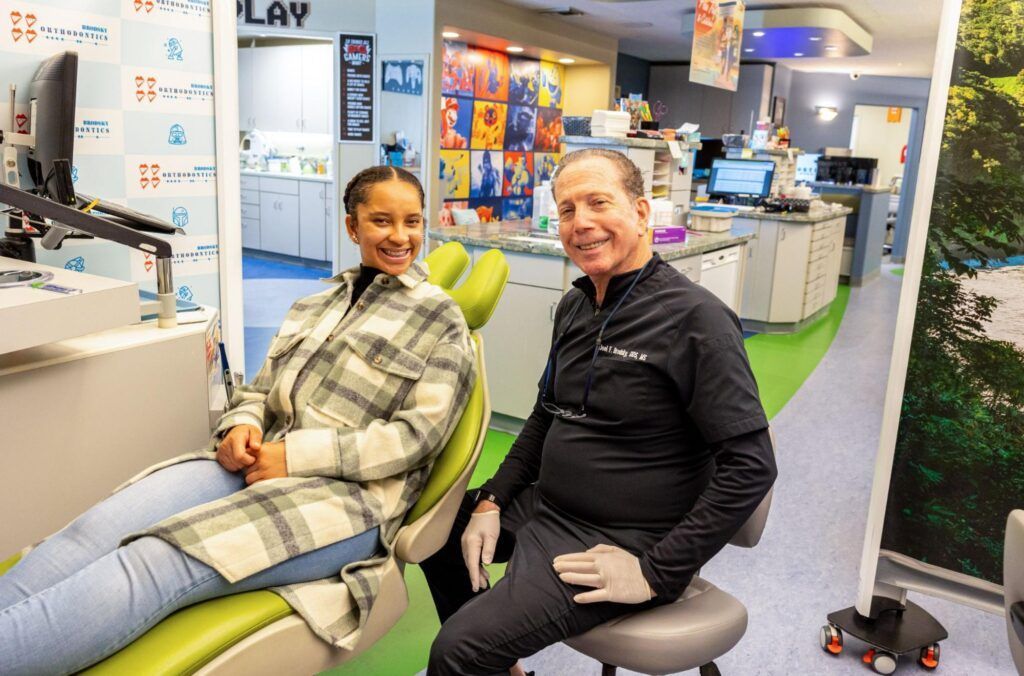 Two people sit on dental chairs smiling in a bright dental clinic showroom.