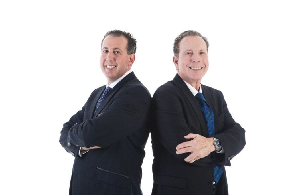 Two men in dark suits standing back-to-back with arms crossed on a white background