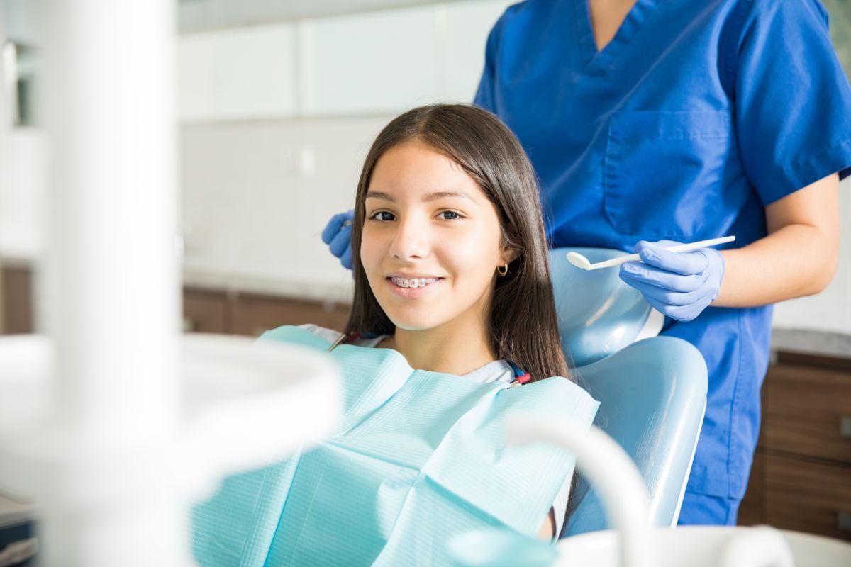 Patient in a dental chair with a dentist in blue scrubs preparing treatment