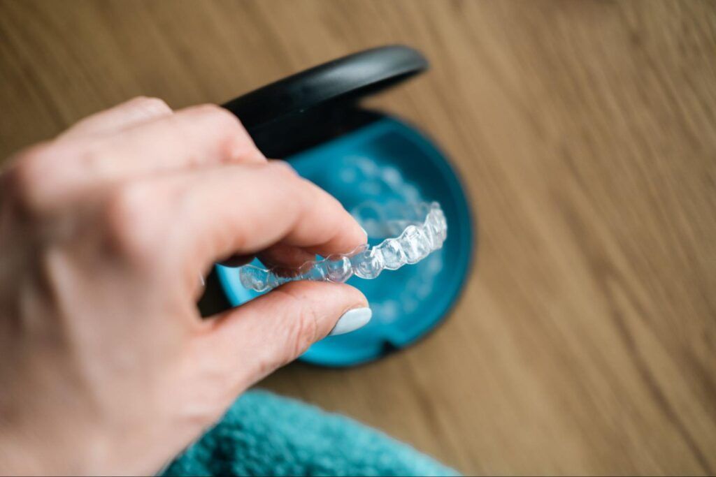 Hand opening a blue pill organizer on a wooden surface