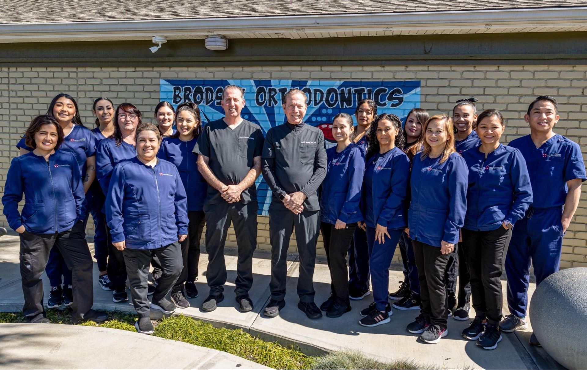 Group of people in blue shirts standing outside a building in front of a donation banner.