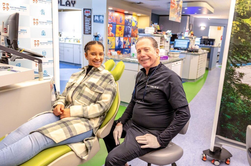 Two people sitting in dental chairs, smiling in a bright clinic waiting area