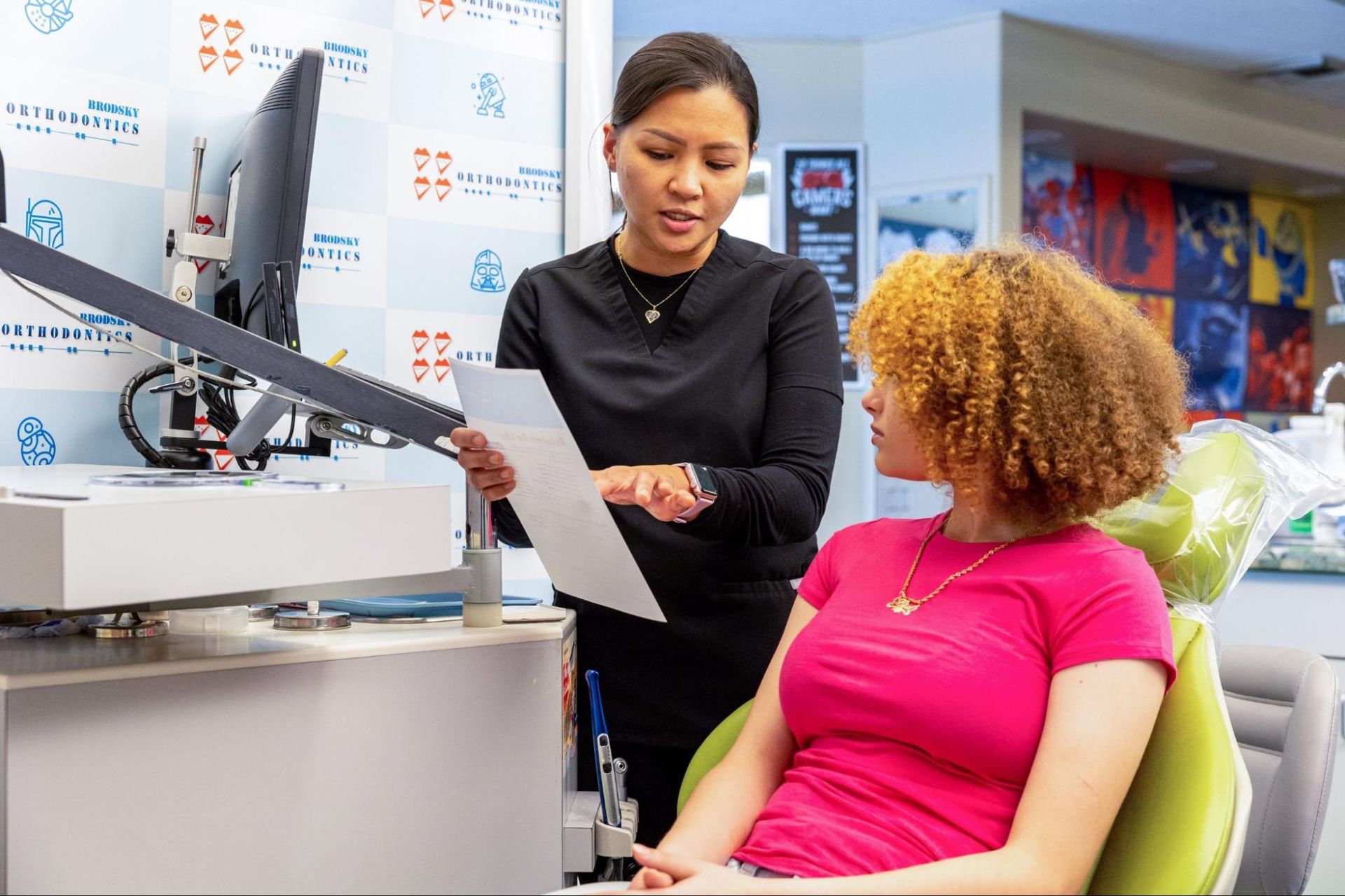 Woman showing a document to a seated patient in a clinic setting