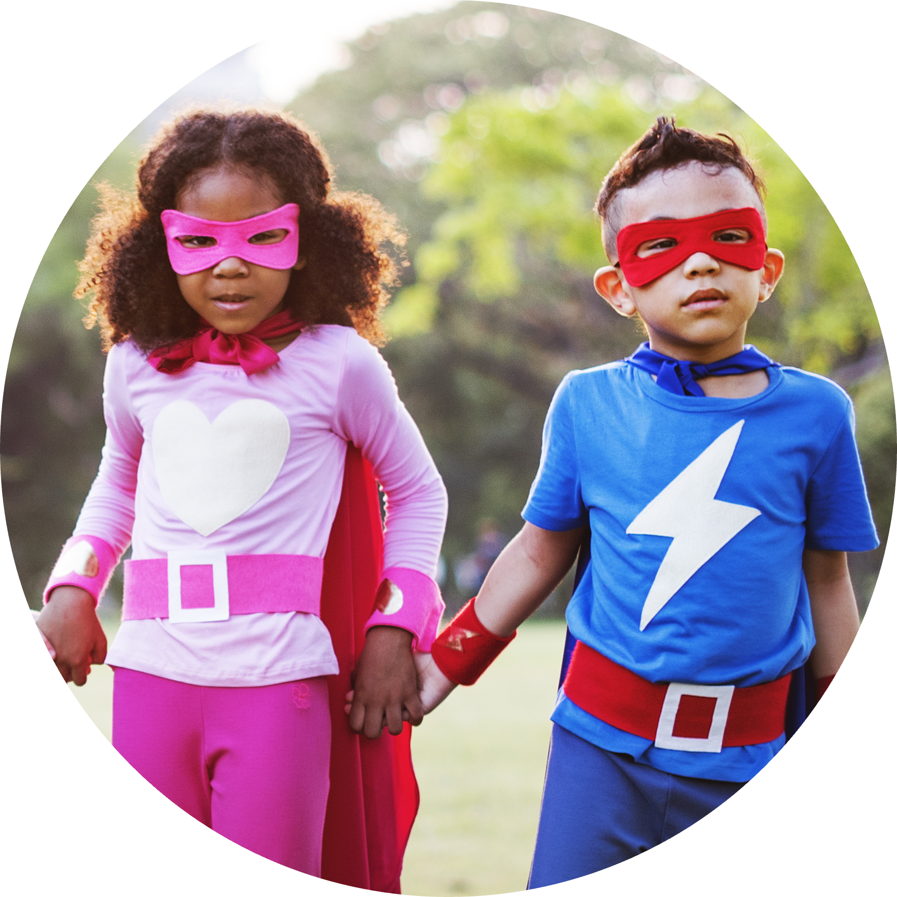 A boy and a girl in superhero costumes are holding hands