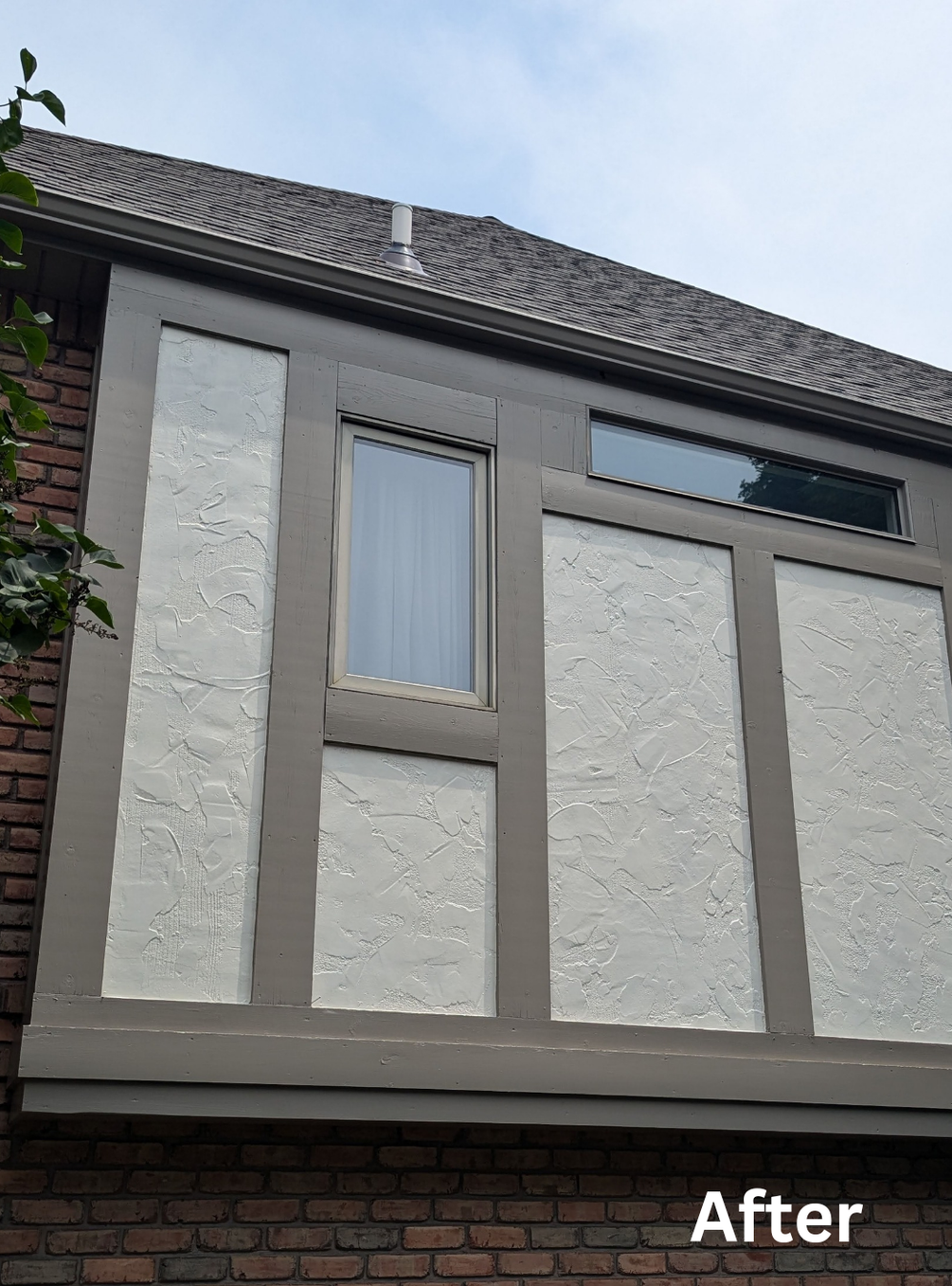 House exterior with gray textured wall panels and a small window under a dark roofline.