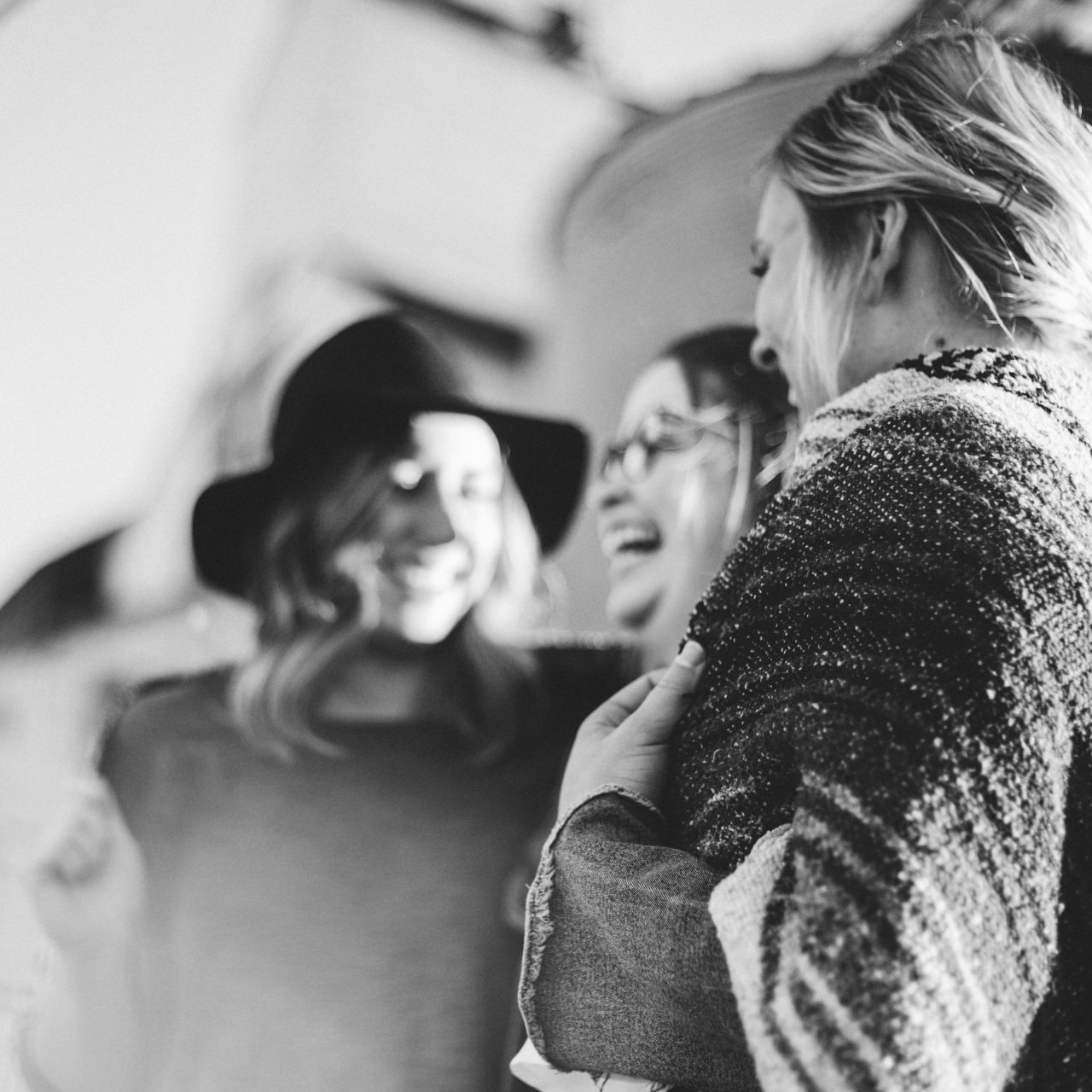 A group of women are standing next to each other and laughing in a black and white photo.
