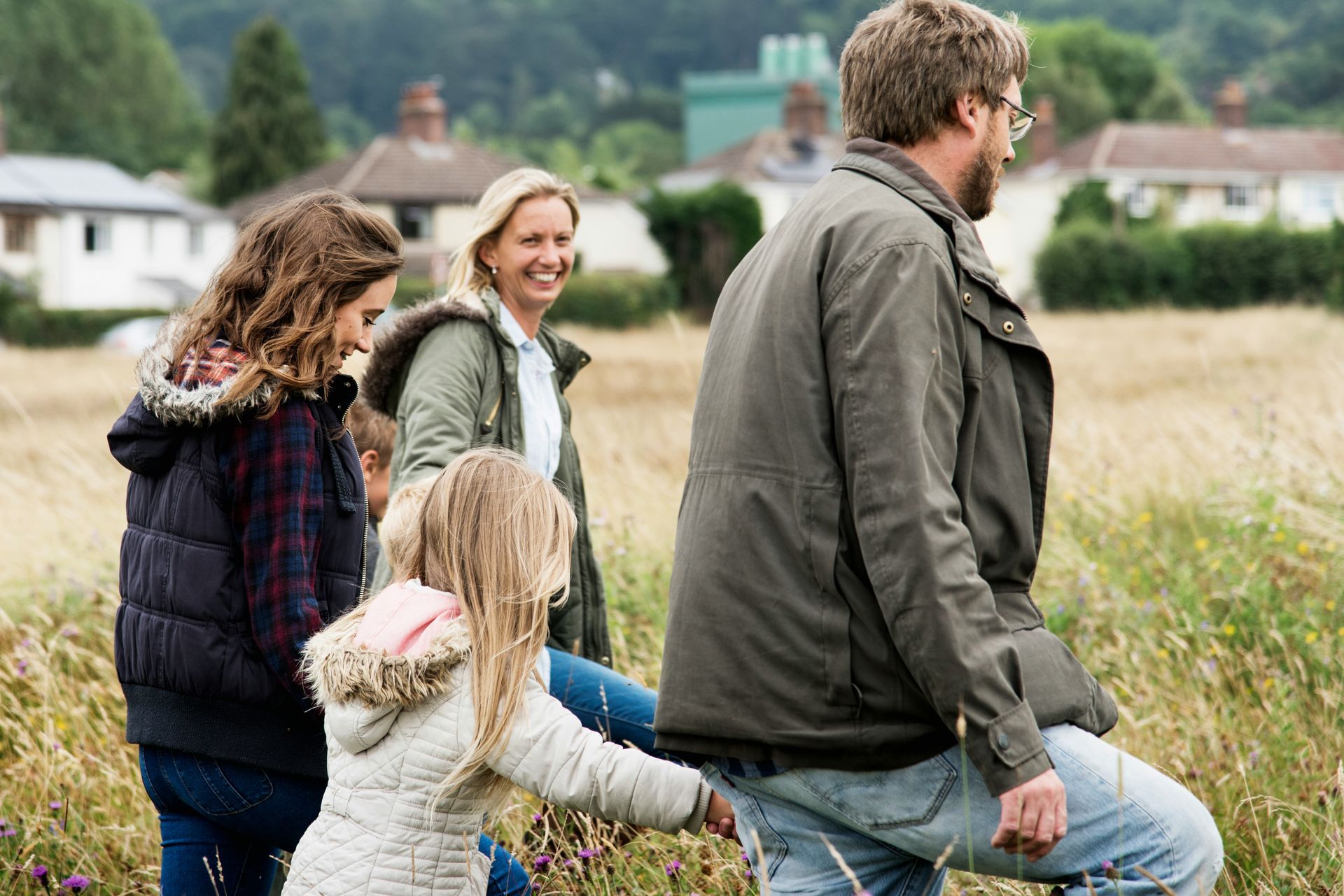 Family loading luggage into a car trunk; smiling people gather outdoors.