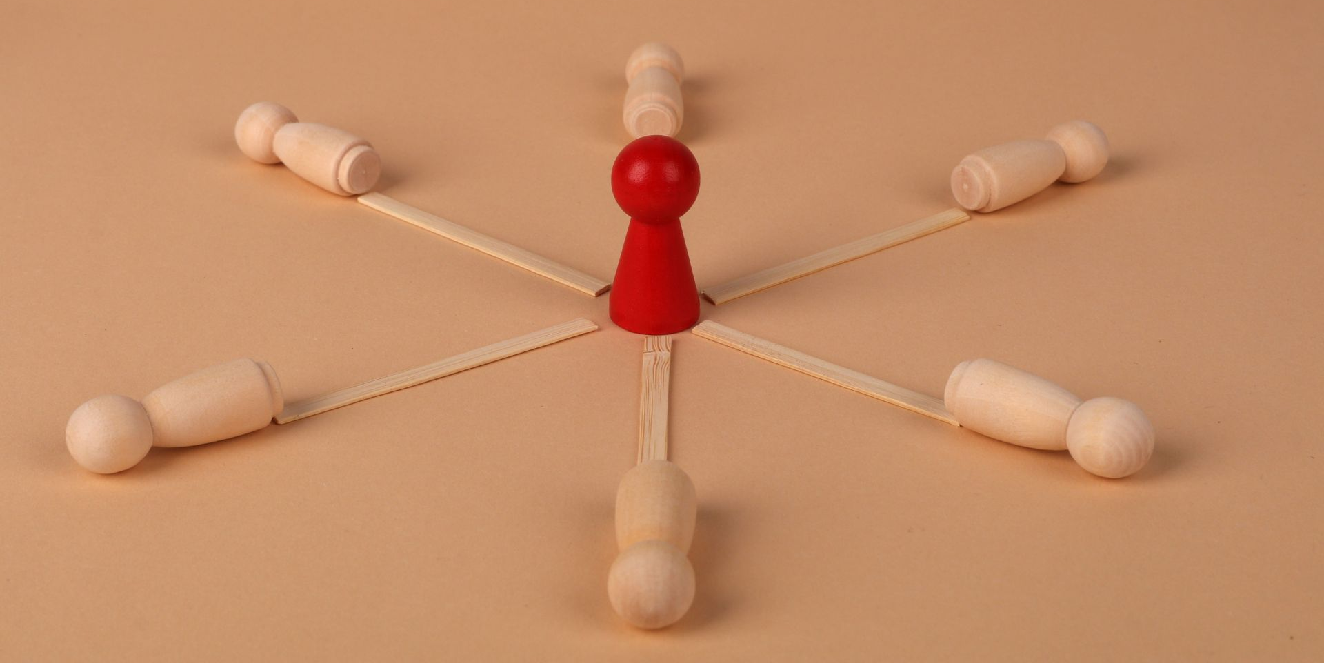 Red pushpin with six white pushpin figures arranged around it on a beige background