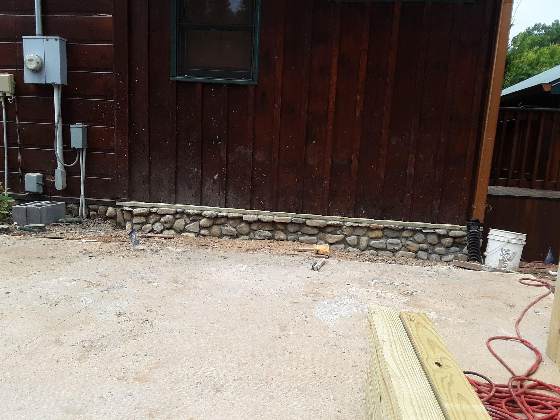A stone wall is being built in front of a wooden building.