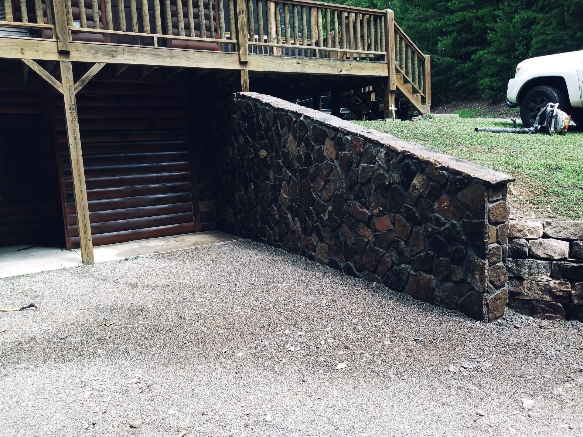 A stone wall with a wooden deck in the background