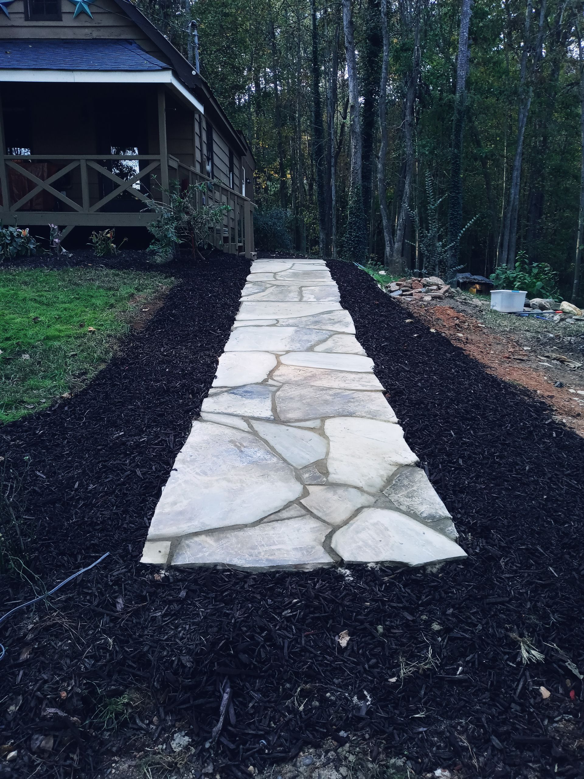 A stone walkway leading to a house in the woods
