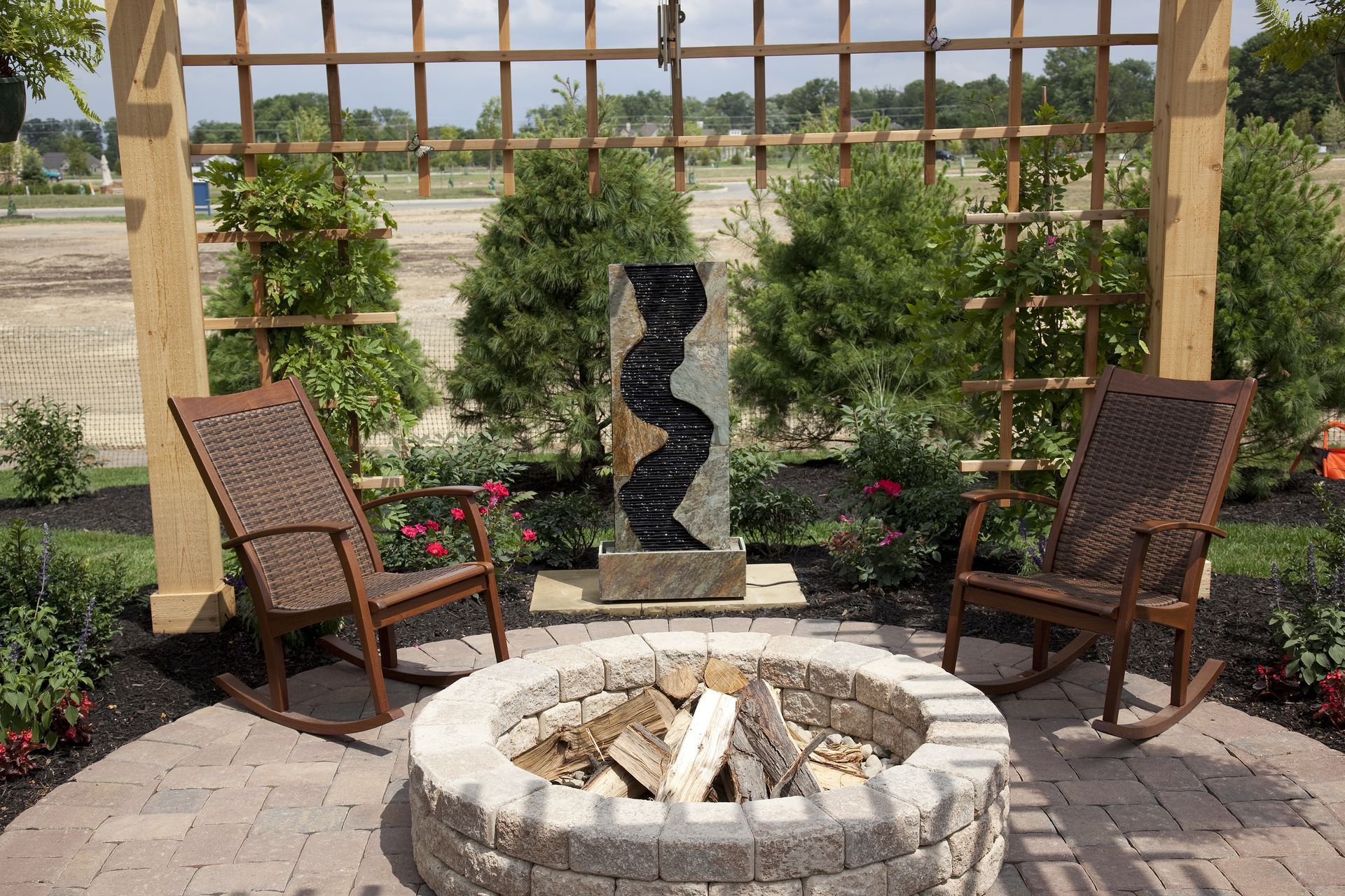A fire pit with rocking chairs and a fountain in the background