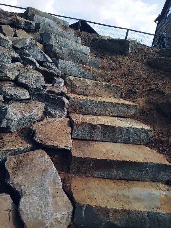 A set of stairs made of rocks going up a hill.