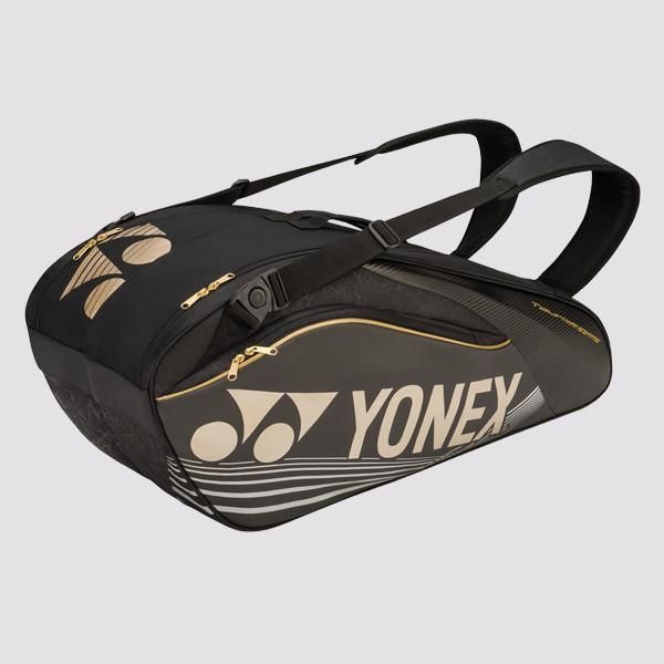 Zwarte Yonex sporttas met gouden accenten en schouderbanden.