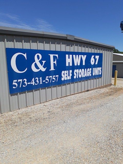 Blue C&F Hwy 67 self storage sign with phone number on a metal building wall