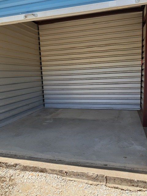 Empty storage unit with open roll-up door and concrete floor
