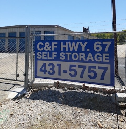 Blue sign for “C&E Hwy. 67 Self Storage” with phone number 431-5757 on a fence outside.