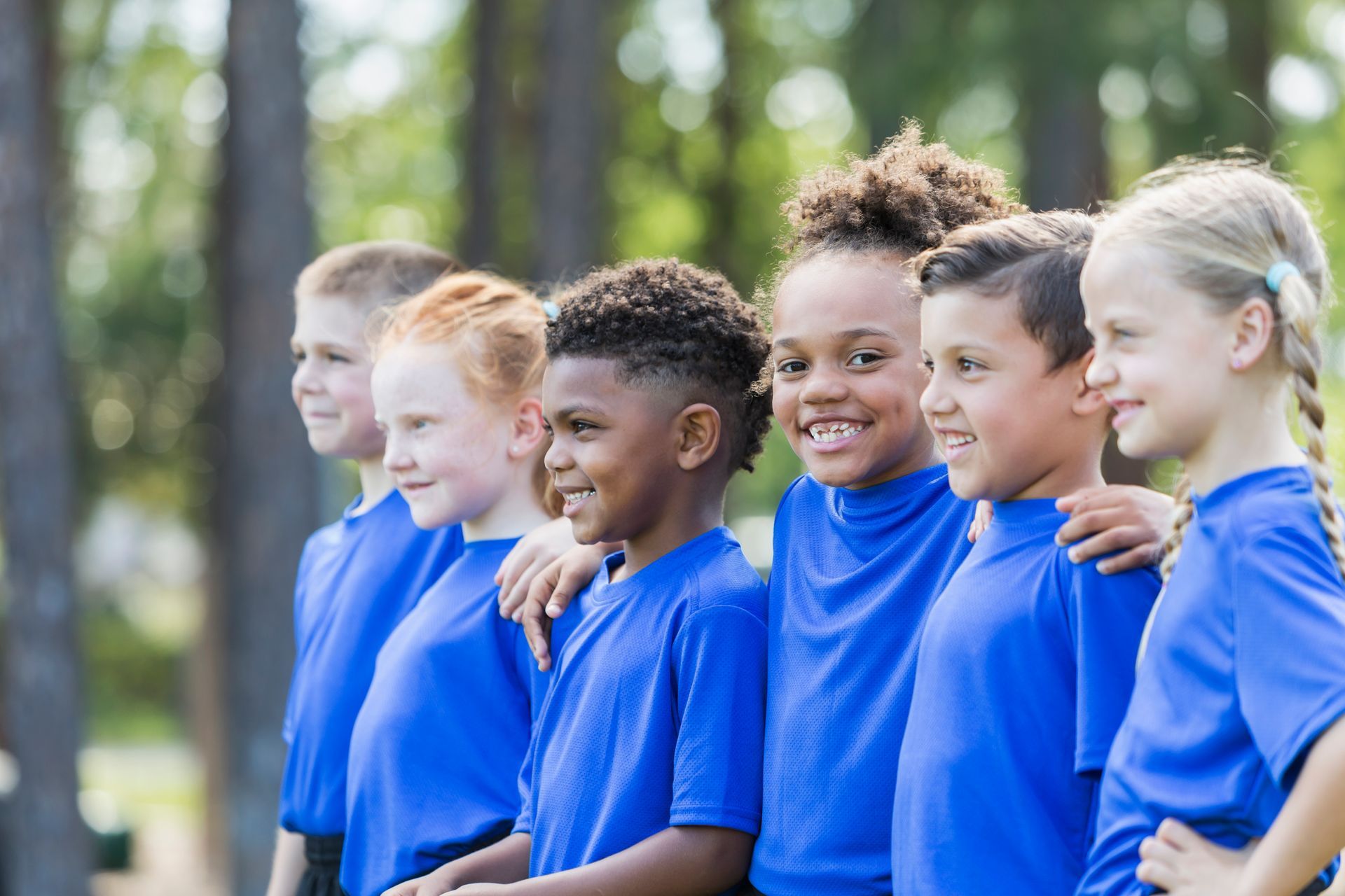 A group of children in blue shirts are standing in a row.