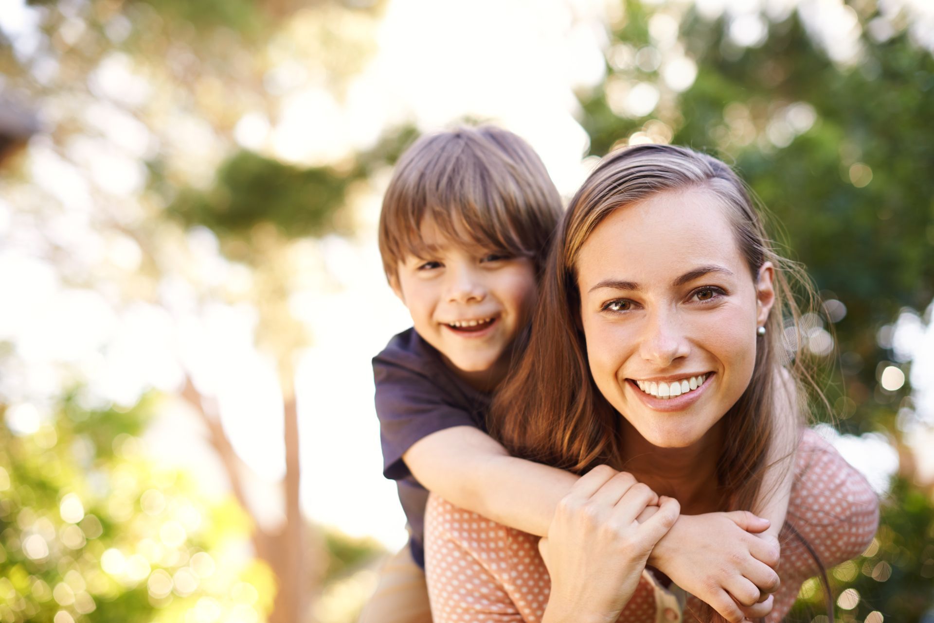 A woman is giving a child a piggyback ride.