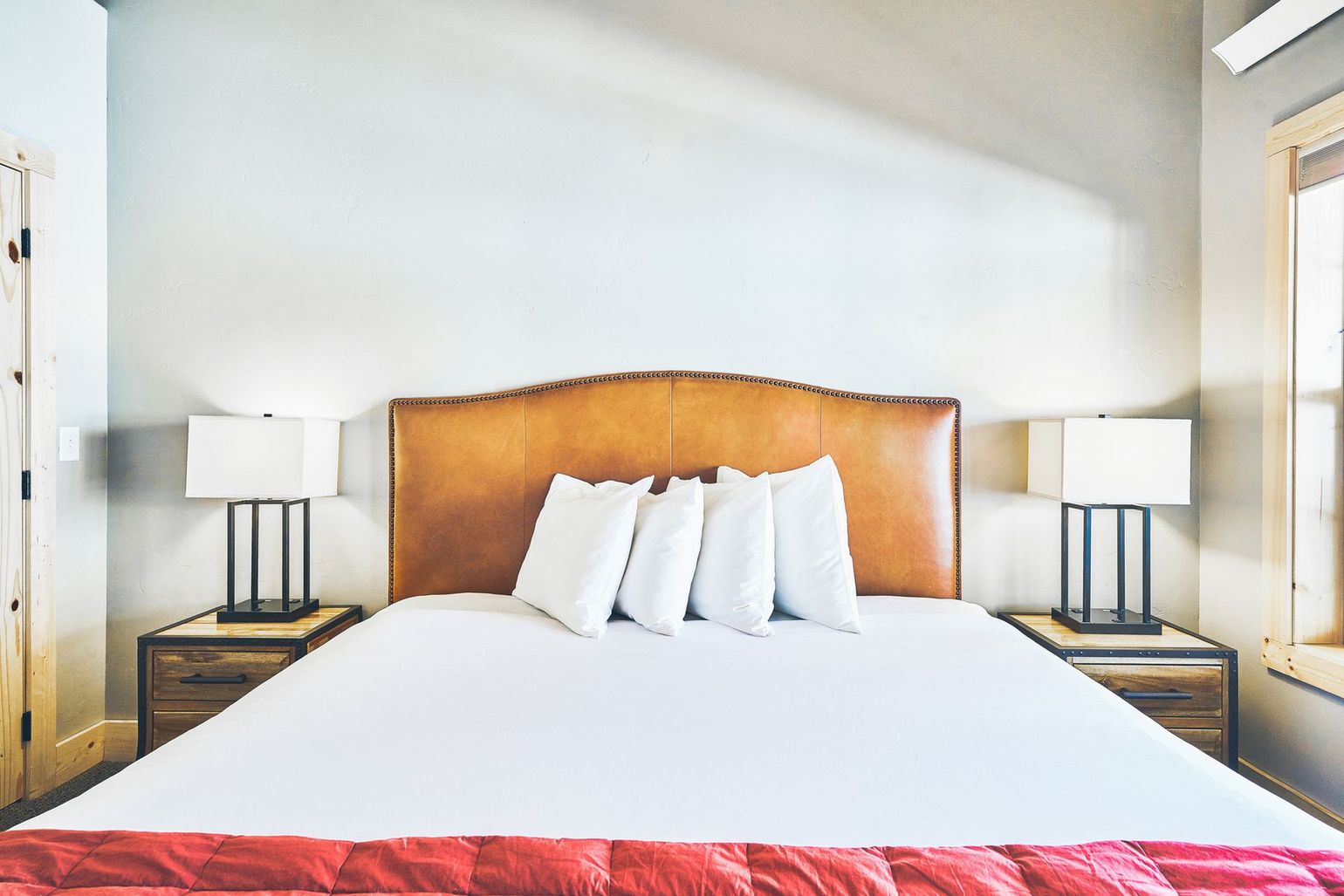 Bright bedroom with a large bed, white linens, wooden headboard, and matching bedside lamps