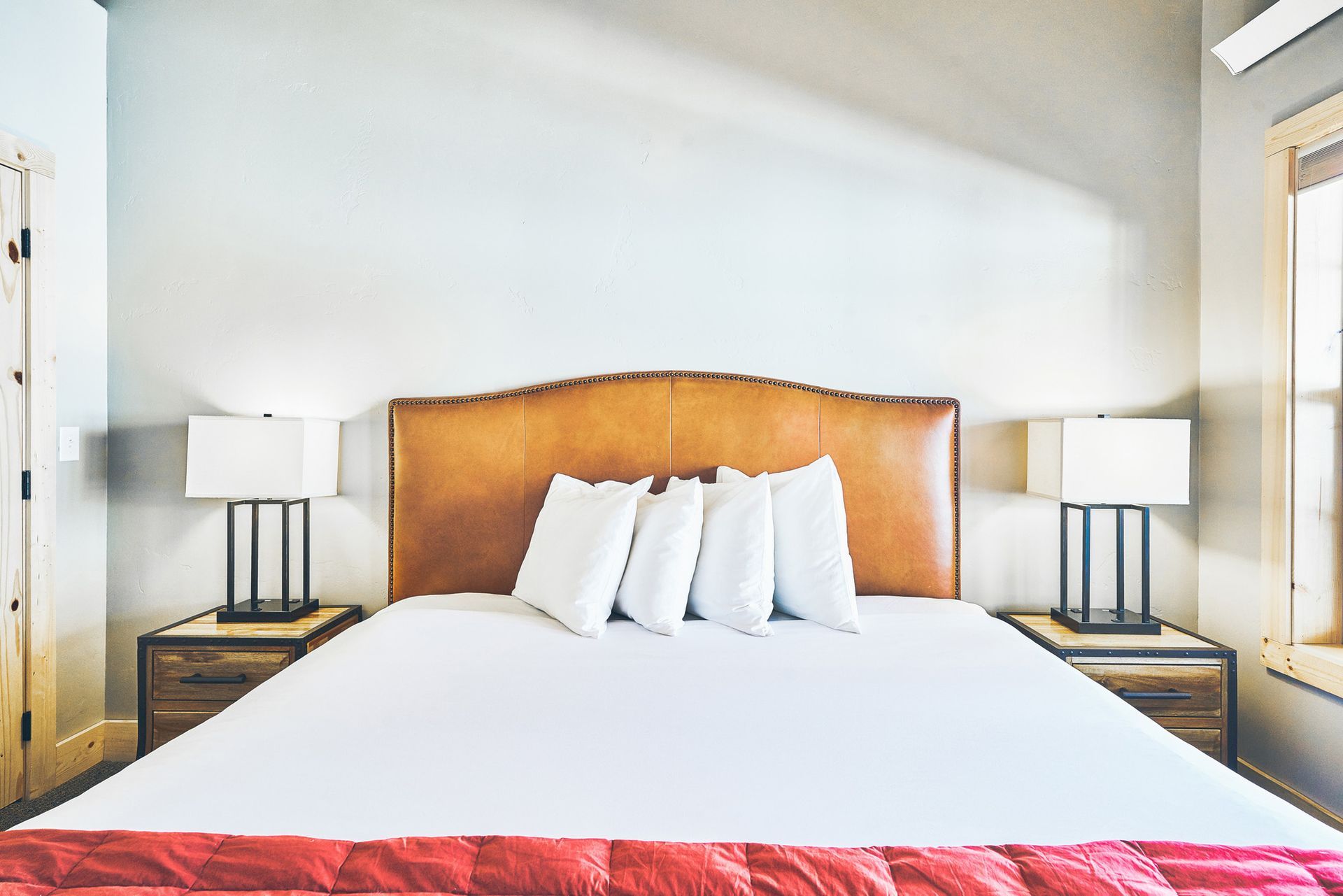 Bright bedroom with a large bed, white linens, wooden headboard, and matching bedside lamps