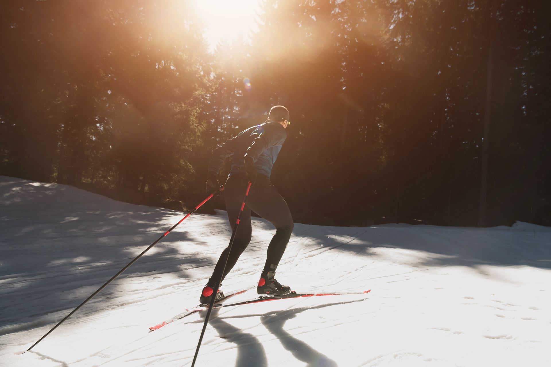 Skier gliding across a snowy slope with ski poles in bright sunlight