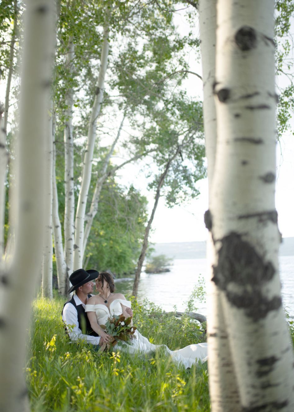 Person holding a child among birch trees by a lakeshore