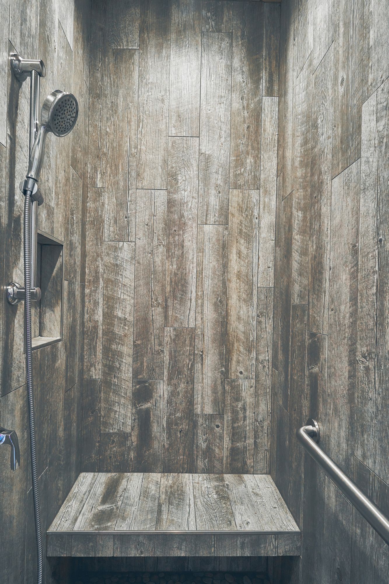 Small, wet concrete shower stall with stained walls, a showerhead on the left, and a ledge in front.