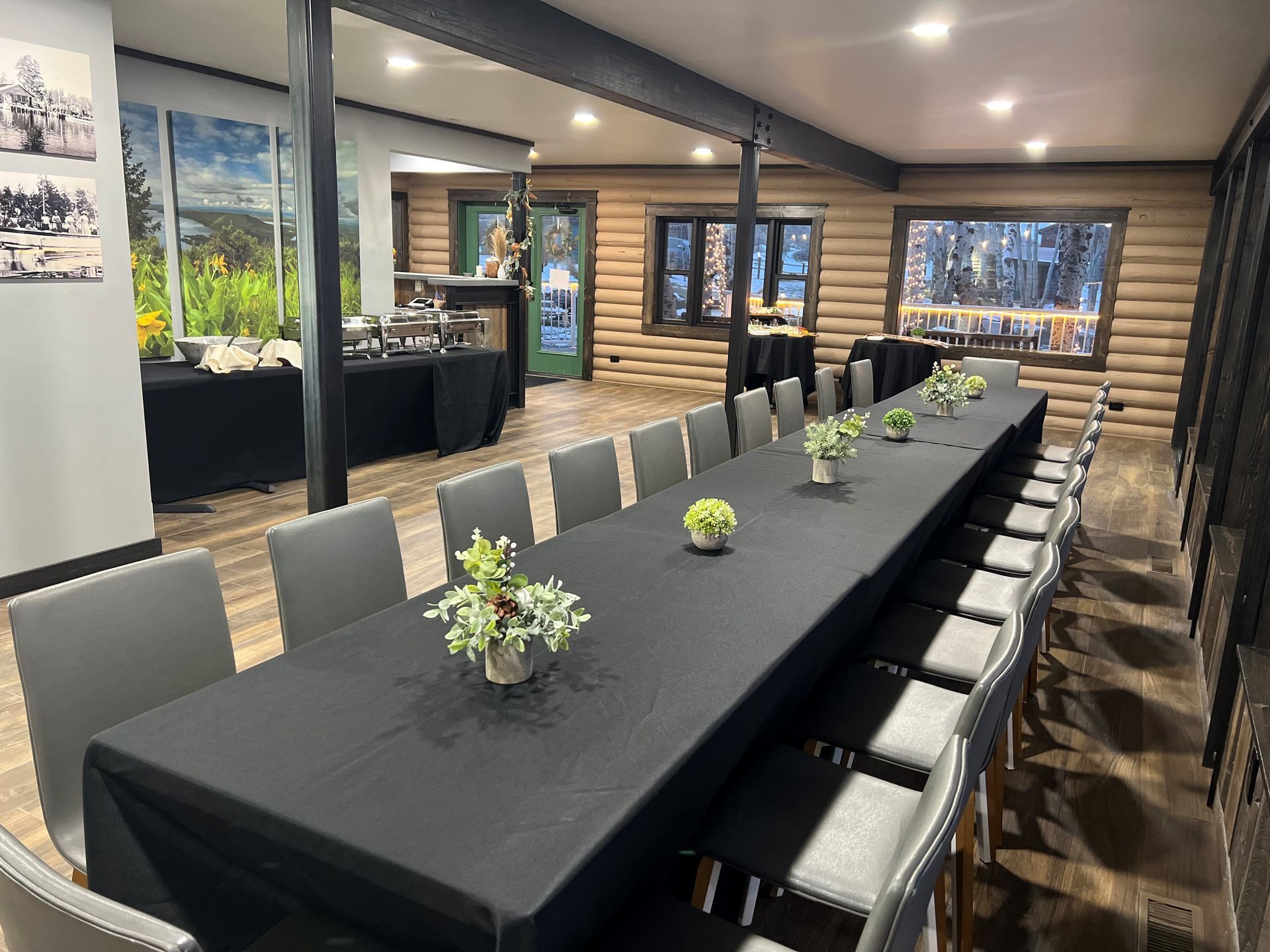 Long banquet table with black tablecloths in a modern log cabin dining room