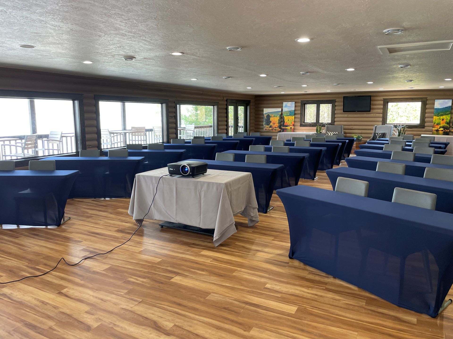 Conference room with blue tablecloth-covered tables arranged on a wood floor